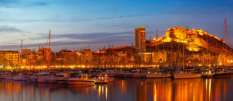 Panorama of port with yachts against cityspace and Castle of Santa Barbara in night  Alicante, Spain